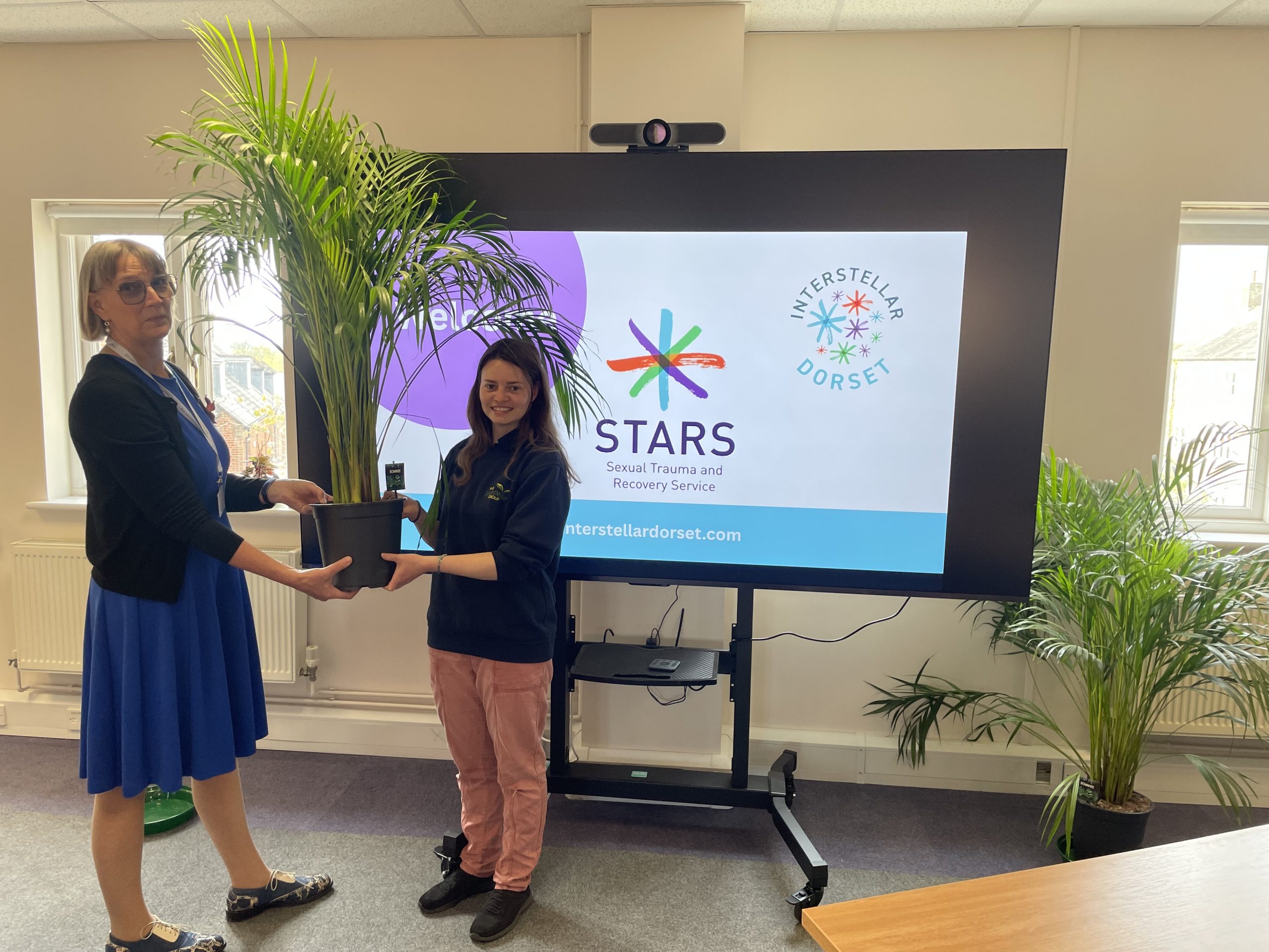 Katie from Poundbury Gardens gives a plant to Helen from STARS Dorset in the new training room at Hammick House.